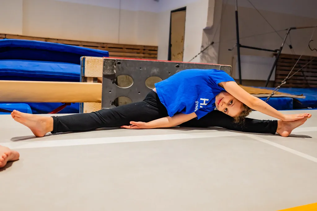 Malá gymnastka HAGA při protahování na žíněnce